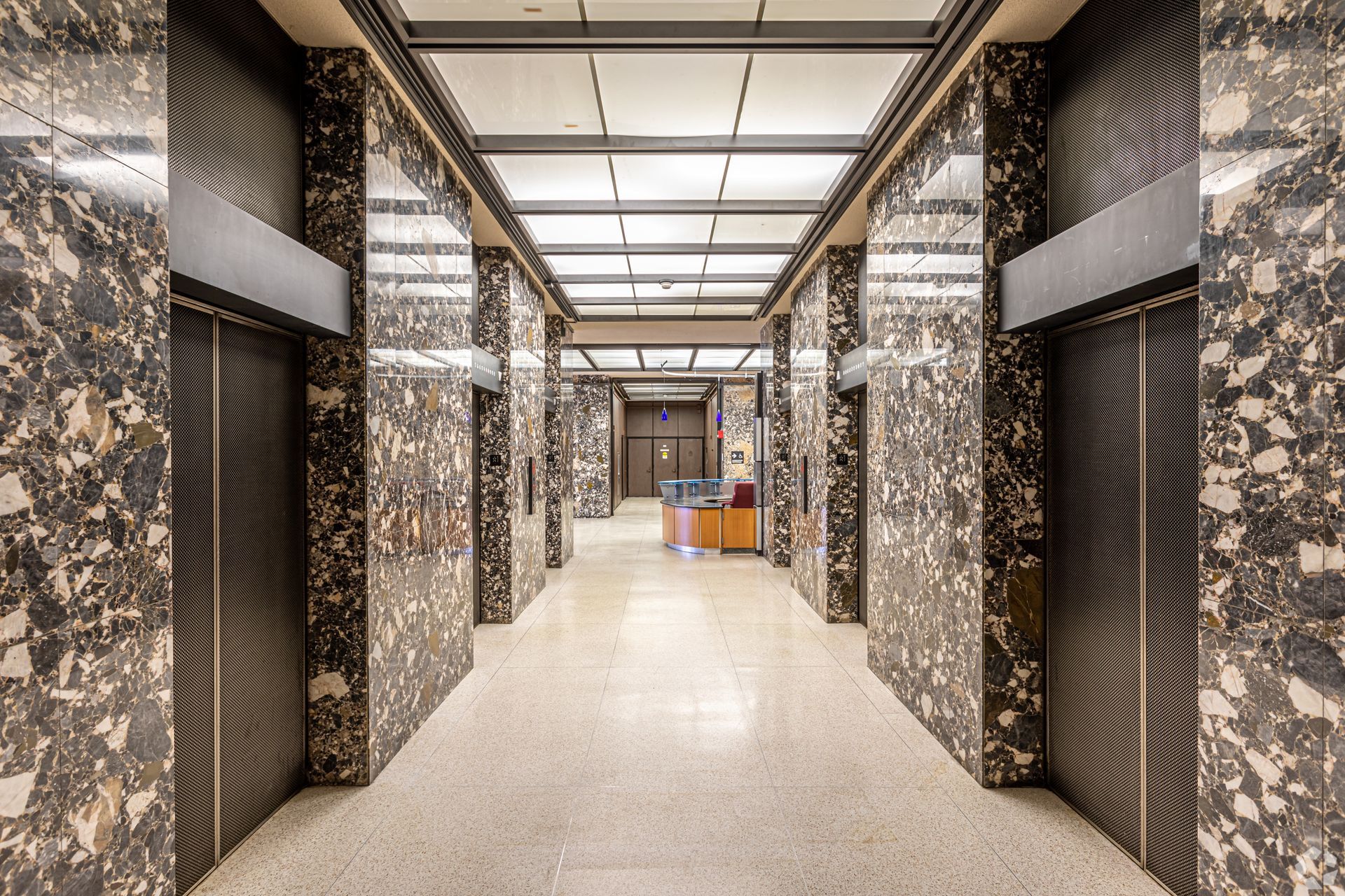 Modern hallway with patterned black-and-white walls, bright ceiling panels, and beige floor tiles