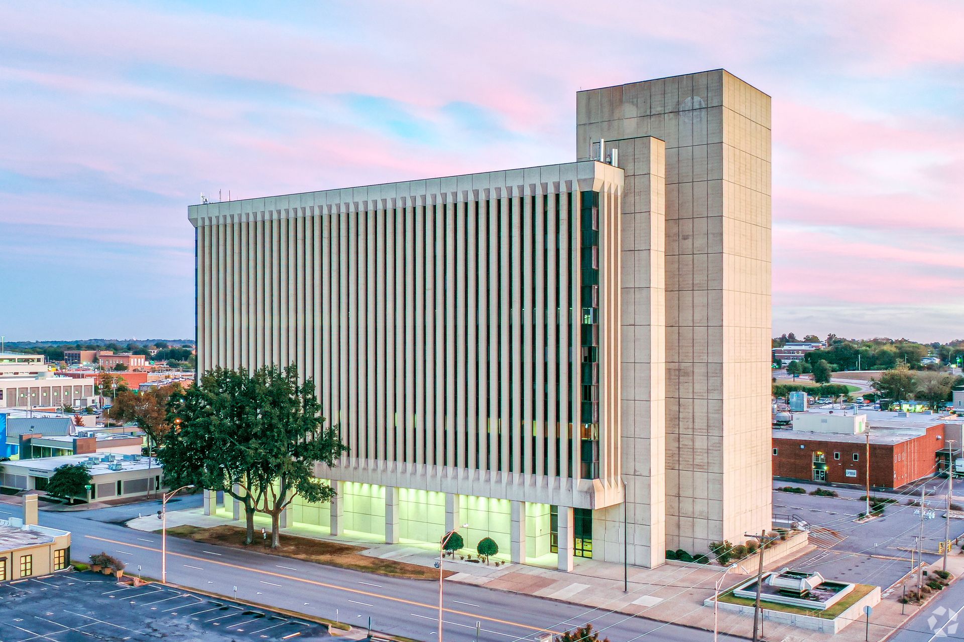 Tall beige office building with vertical stripes at dusk under a pink sky
