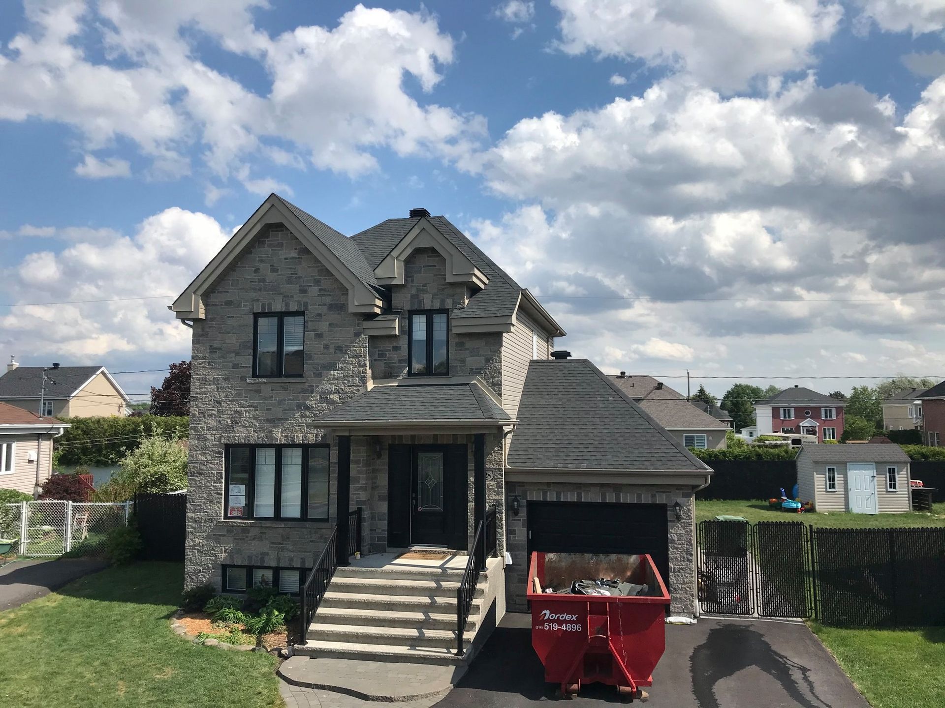 Une grande maison avec une benne à ordures rouge devant elle.