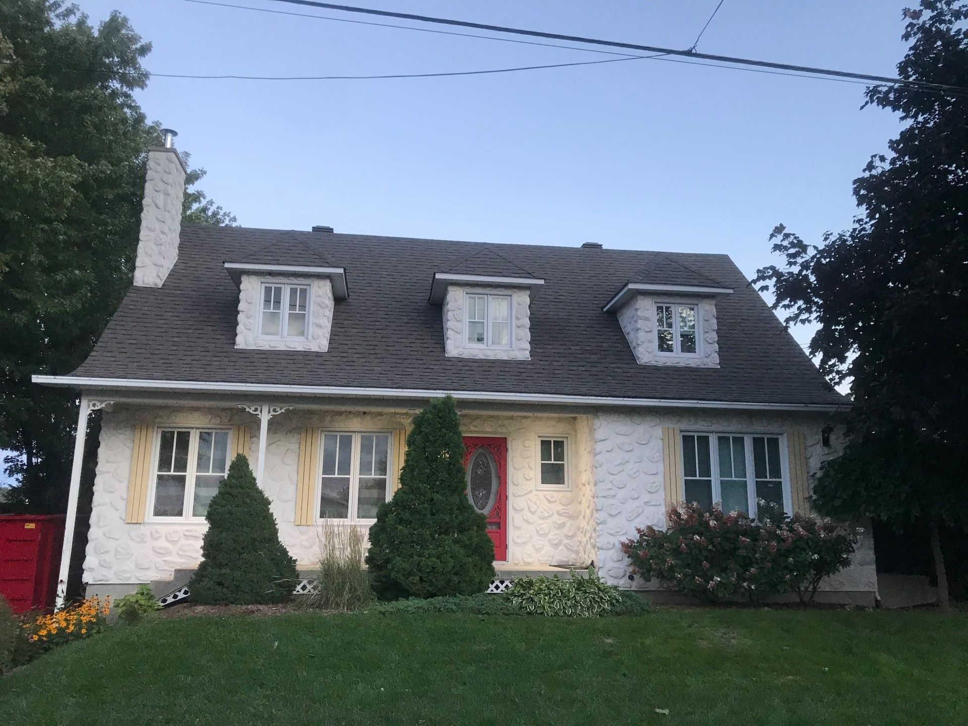 Une maison blanche avec un toit gris et une porte rouge