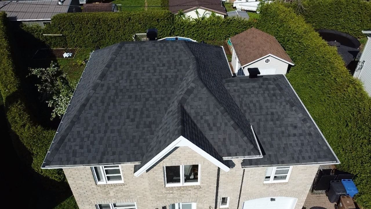 Une vue aérienne d'une maison avec un nouveau toit et un garage.
