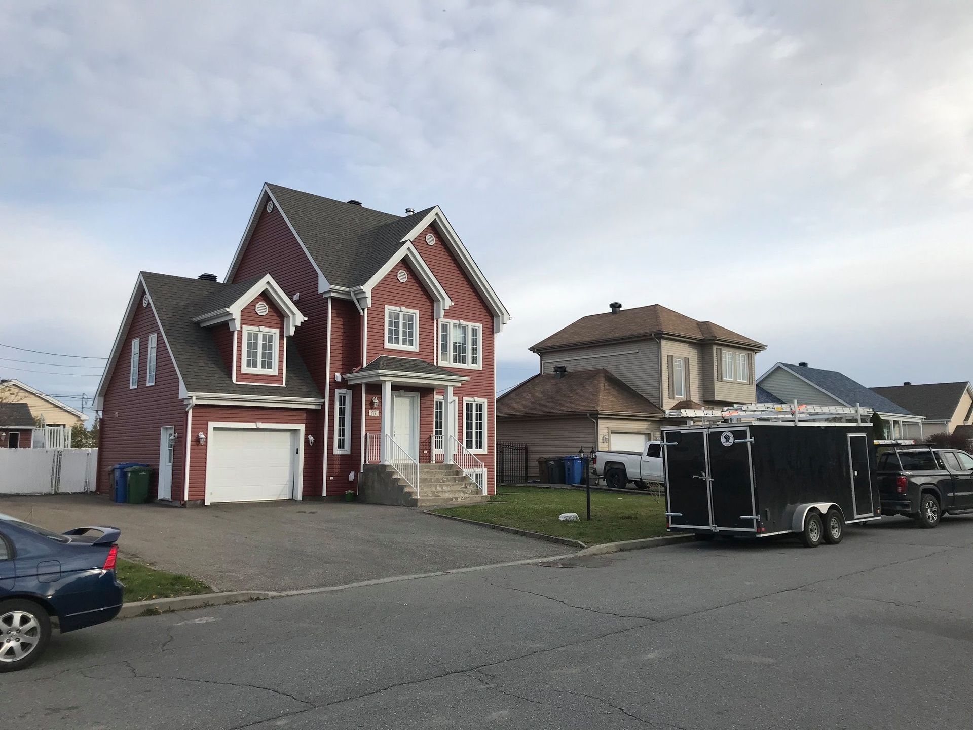 Une maison rouge avec une caravane noire garée devant