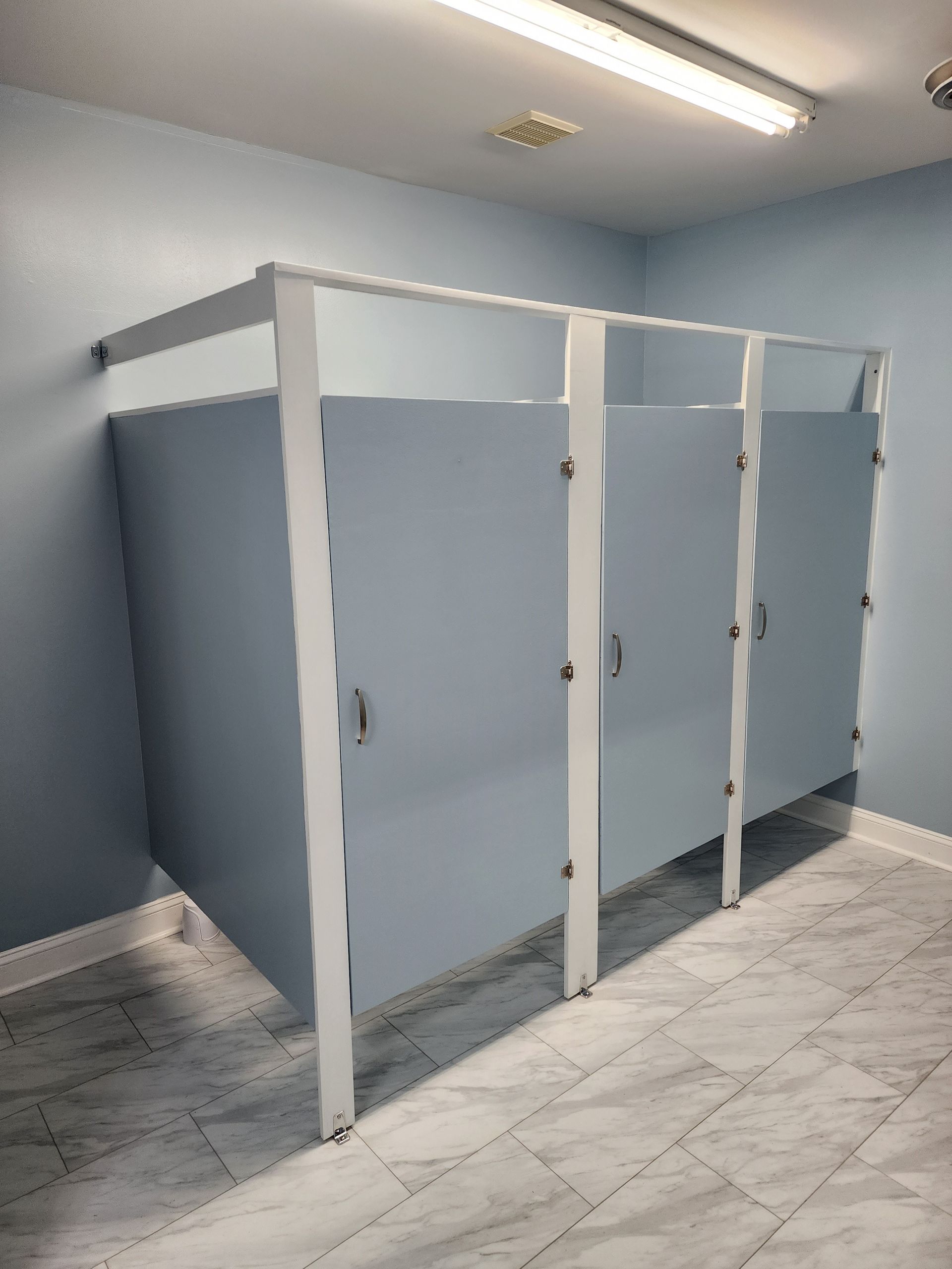 A bathroom with a row of toilet cubicles in it.