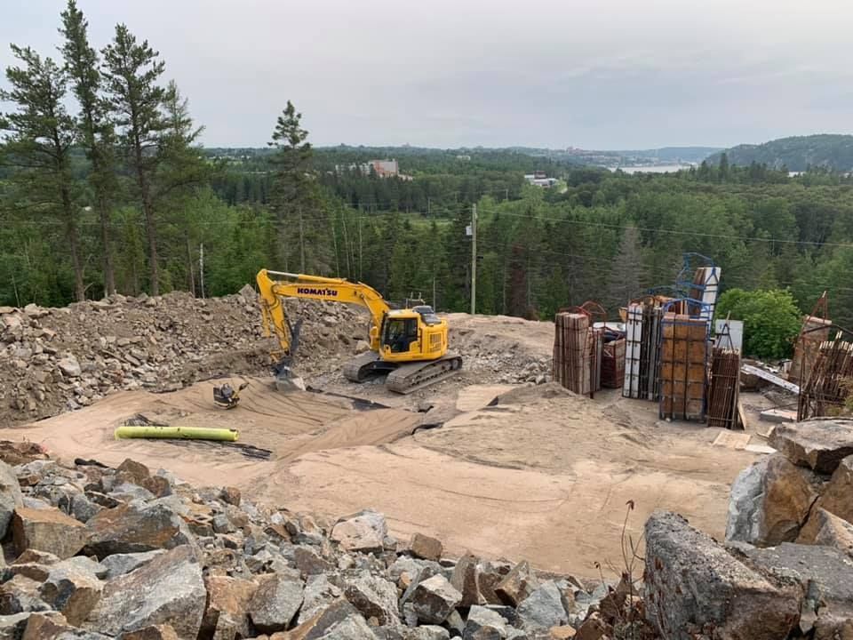 Une excavatrice jaune est assise sur un tas de rochers.
