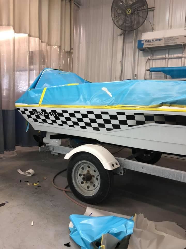 A boat on a trailer is being painted in a garage.
