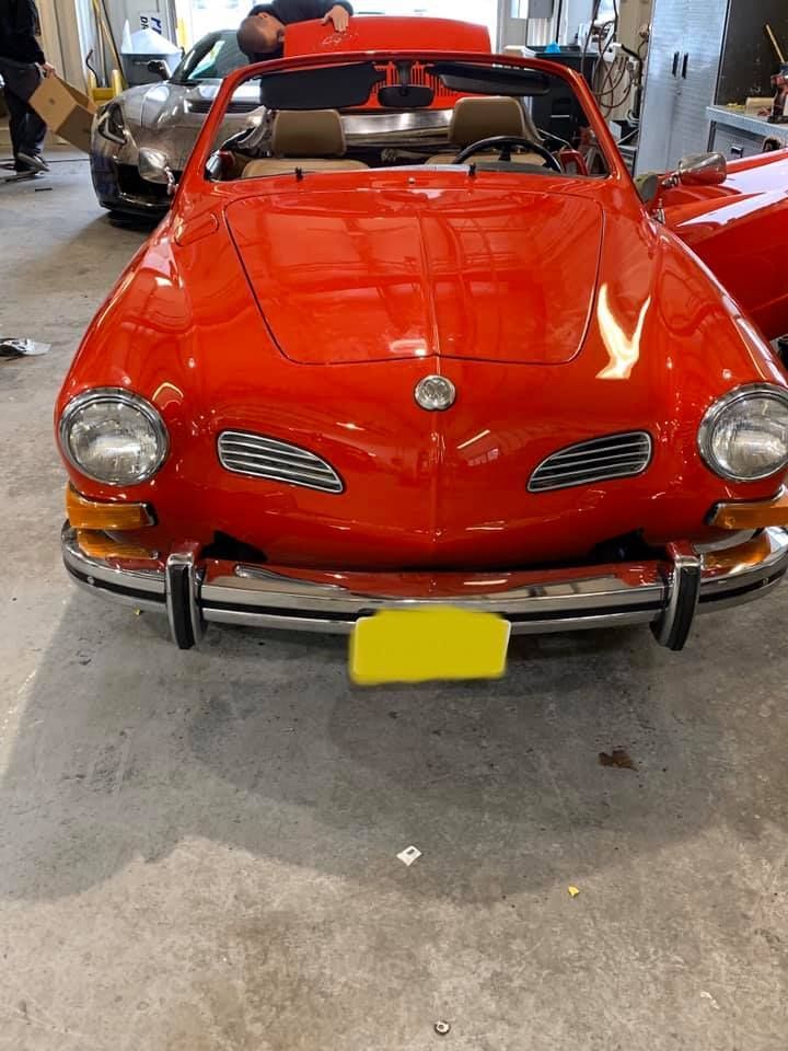 A red car with a yellow license plate is parked in a garage.
