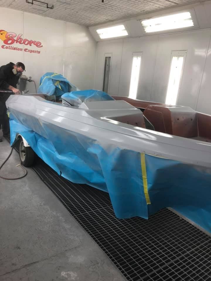 A man is painting a boat in a paint booth.