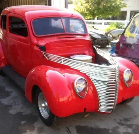 A red car with the hood open is parked on the side of the road