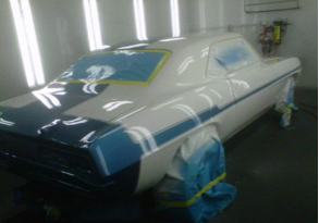 A white car with blue stripes is sitting in a paint booth