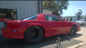 A red car is parked in front of a building