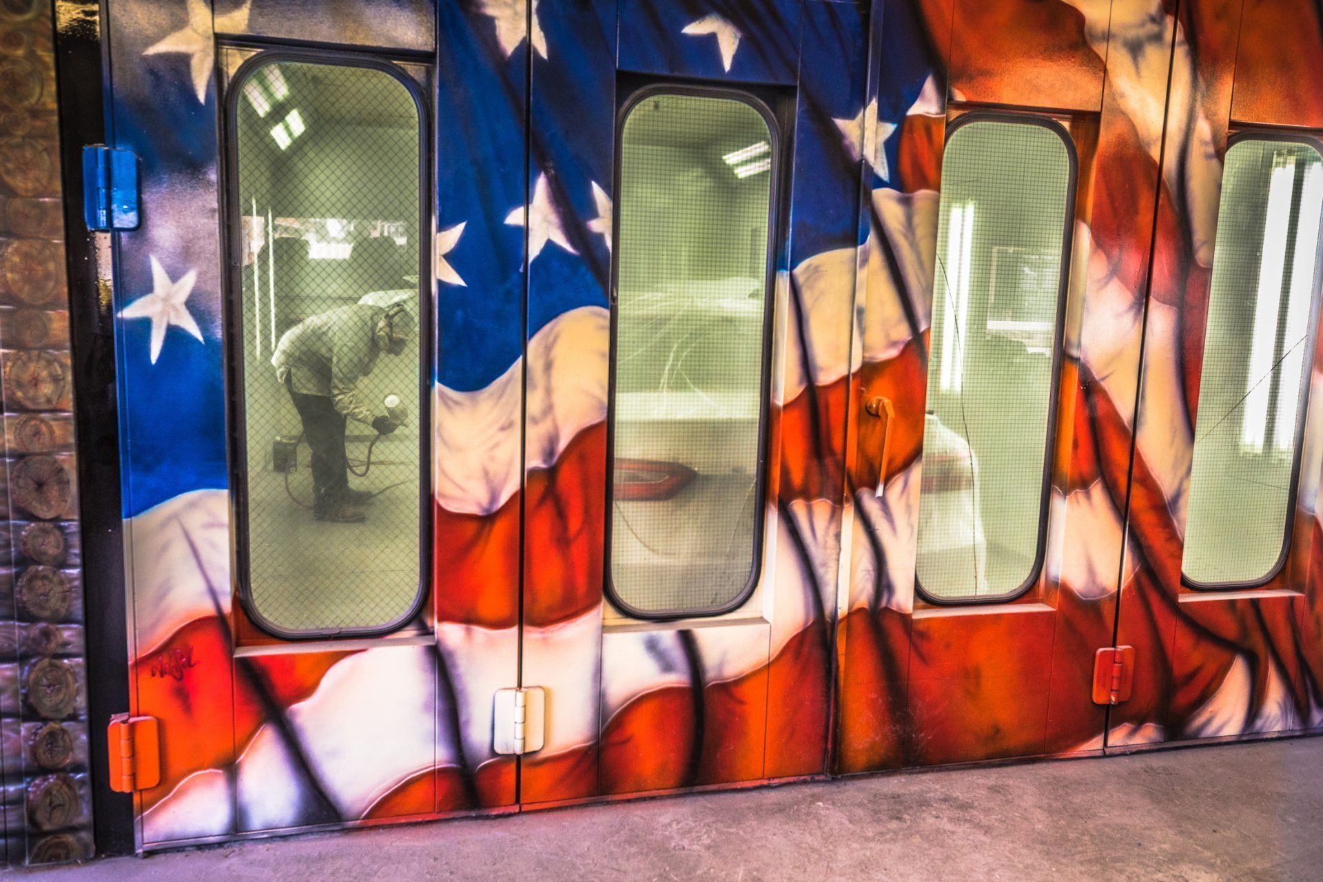 A man is standing in front of a wall with an american flag painted on it.