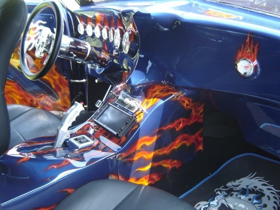 A blue car with flames painted on the dashboard