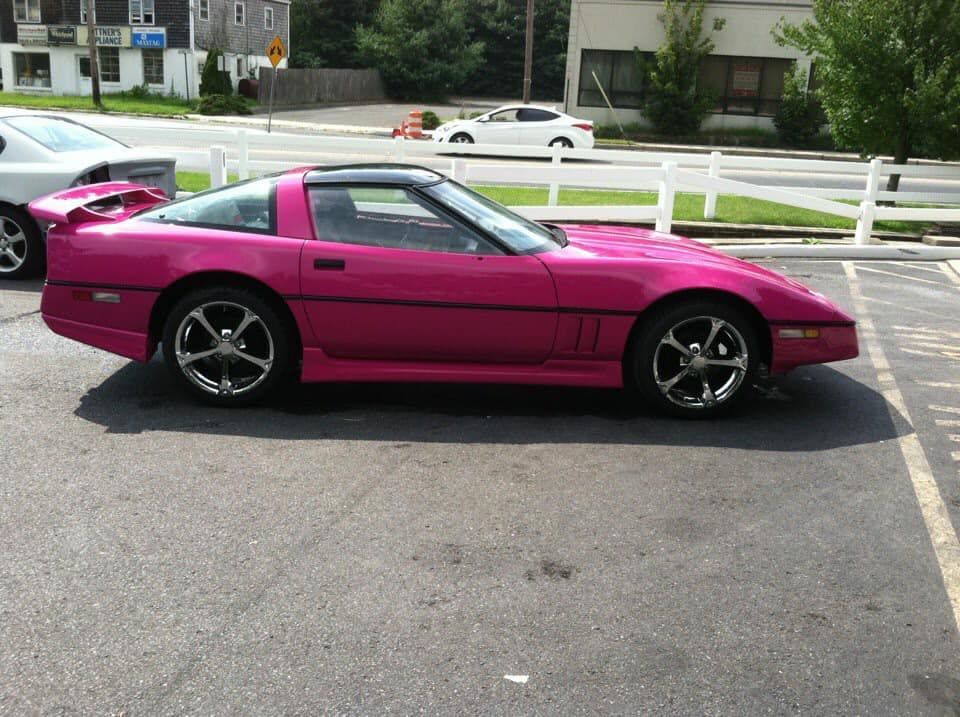 A pink sports car is parked in a parking lot