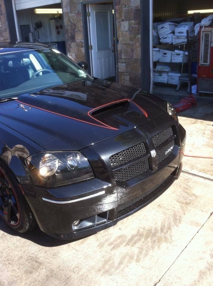 A black dodge charger is parked in front of a garage