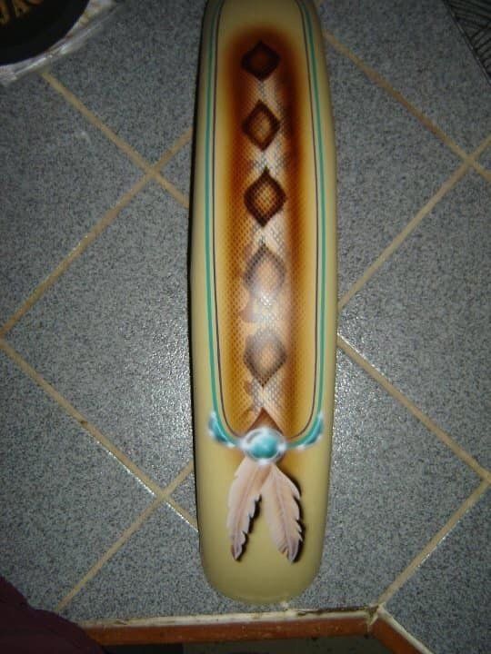 A skateboard with feathers and diamonds painted on it