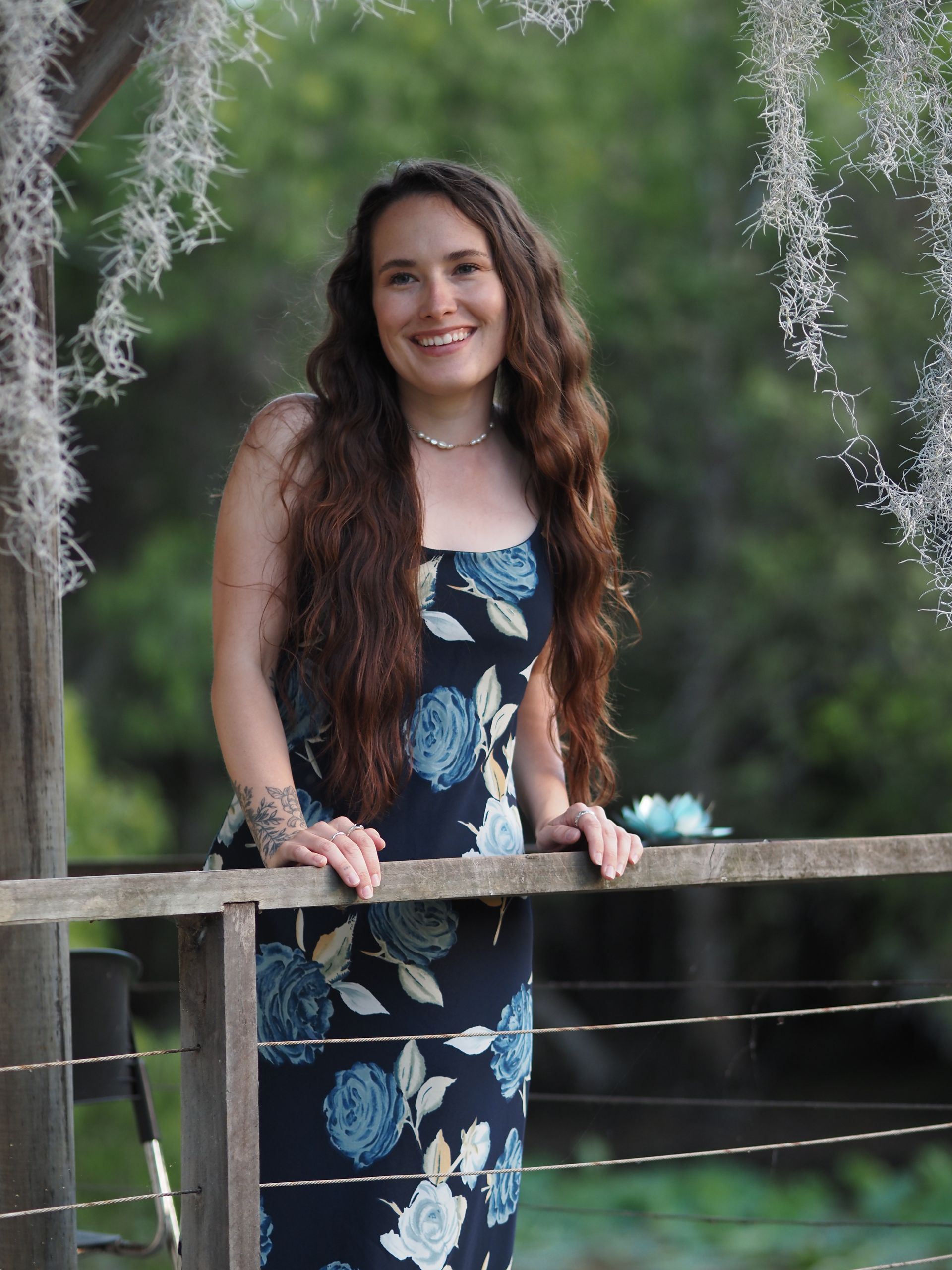 A woman in a floral dress is leaning on a railing.