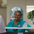 A woman in a green scrub is smiling at the camera