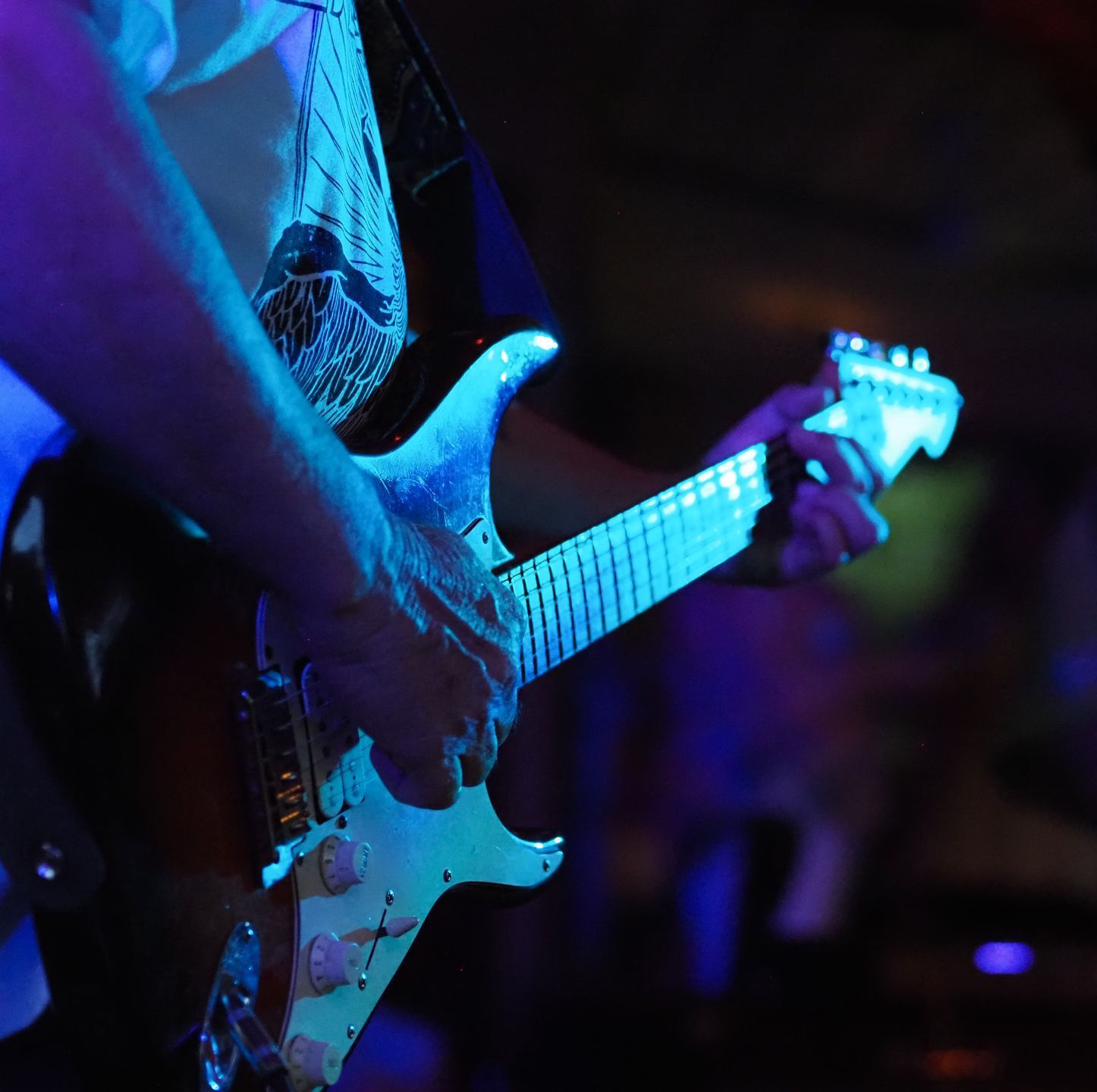 A man is playing an electric guitar in a dark room