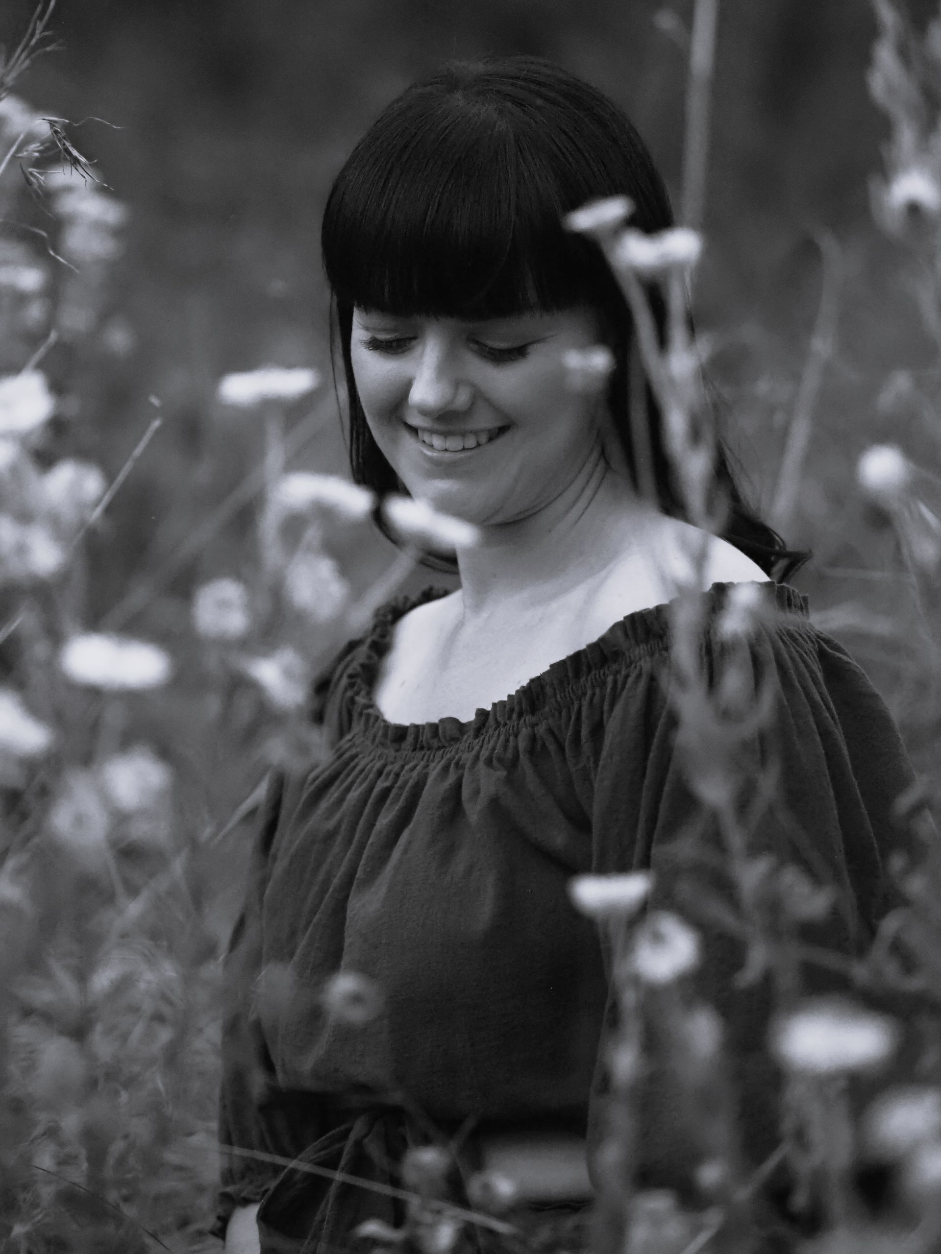 A woman is standing in a field of flowers in a black and white photo.