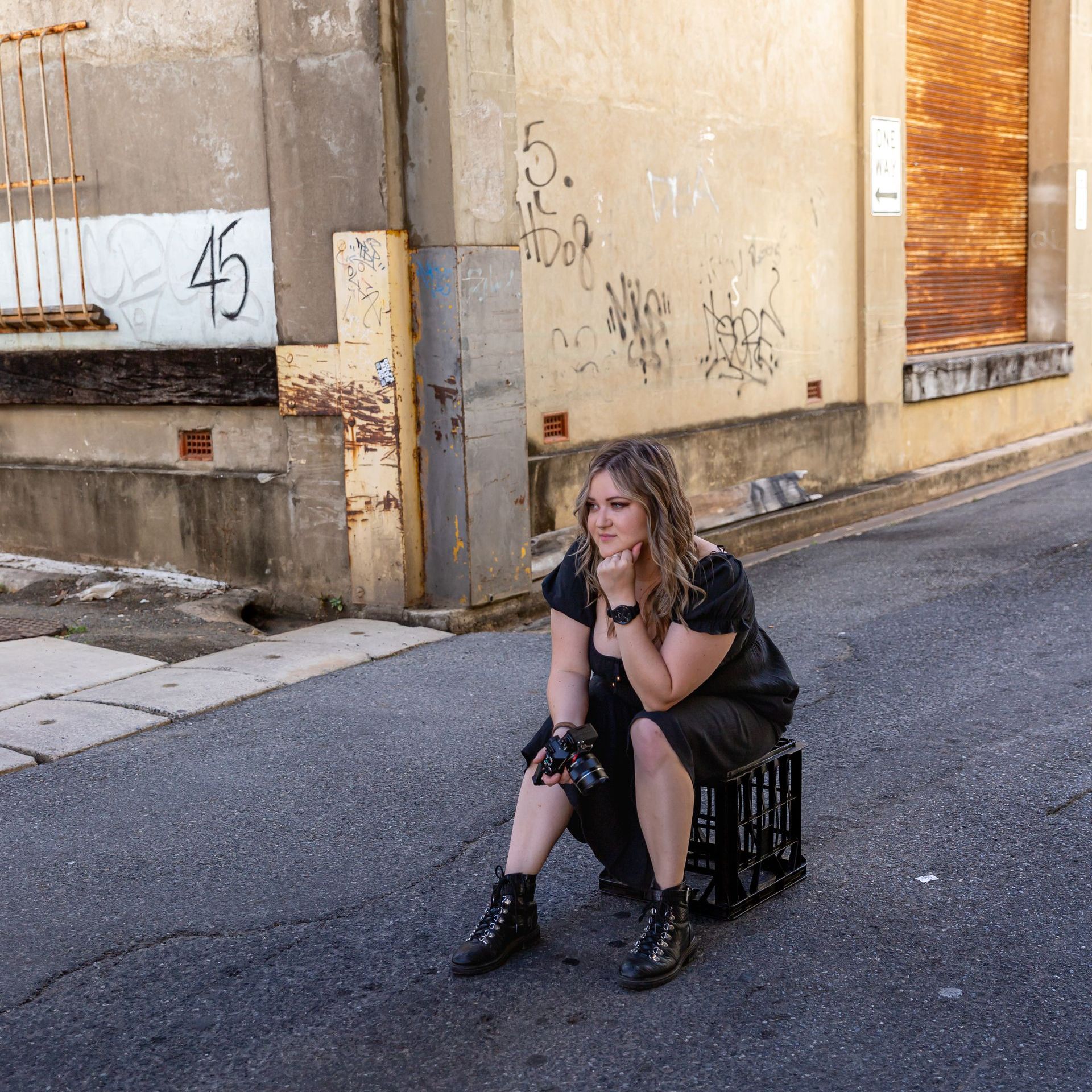 A woman sits on a crate with the number 45 on the wall behind her