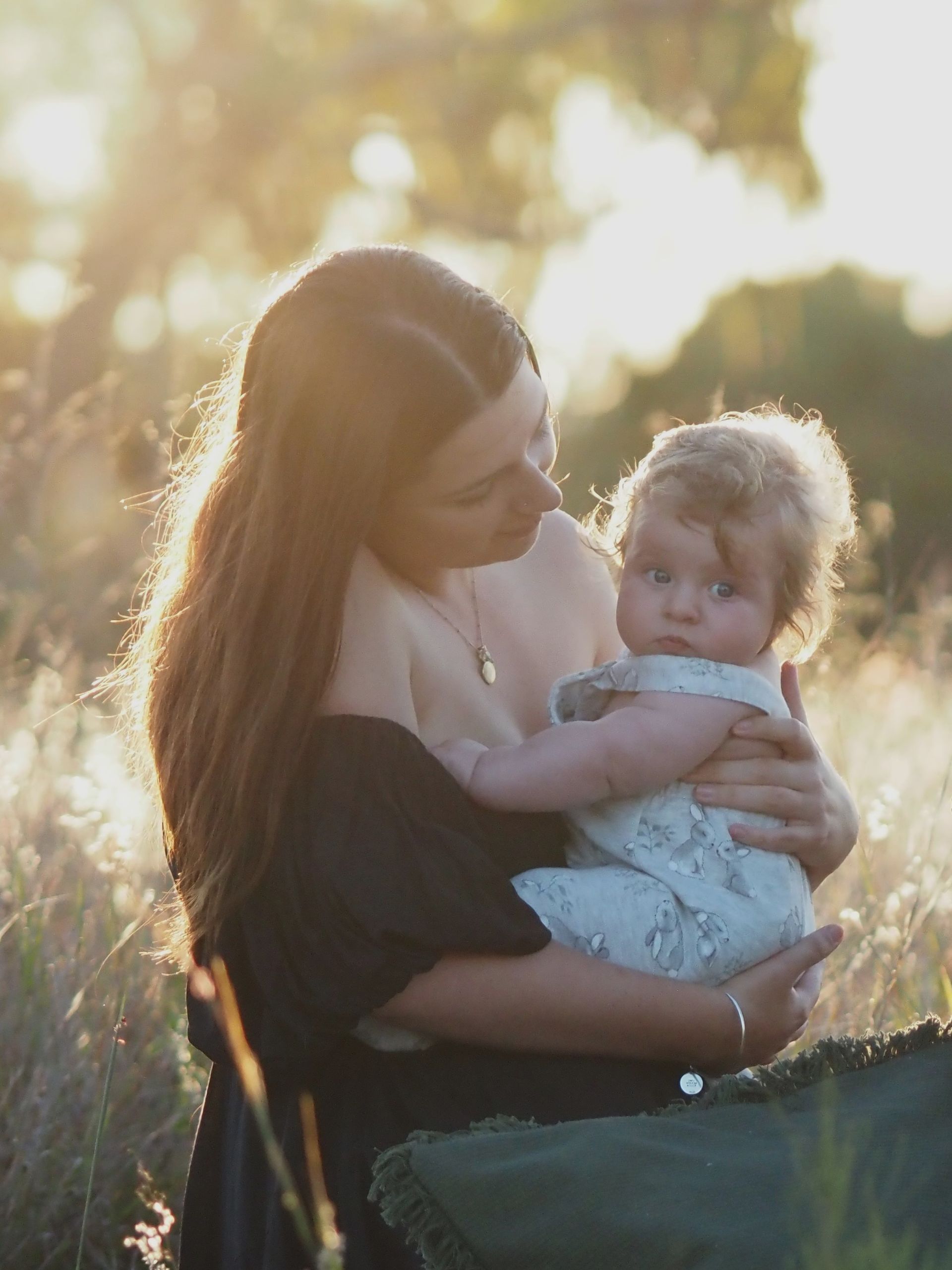 A woman is holding a baby in her arms in a field.