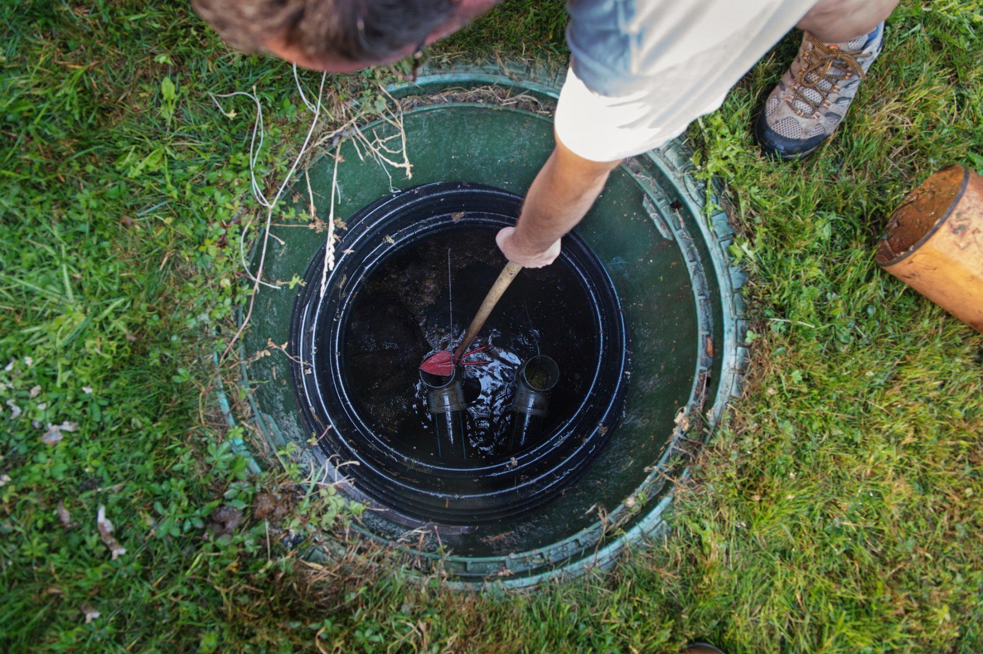 A man is cleaning a septic tank with a plunger.