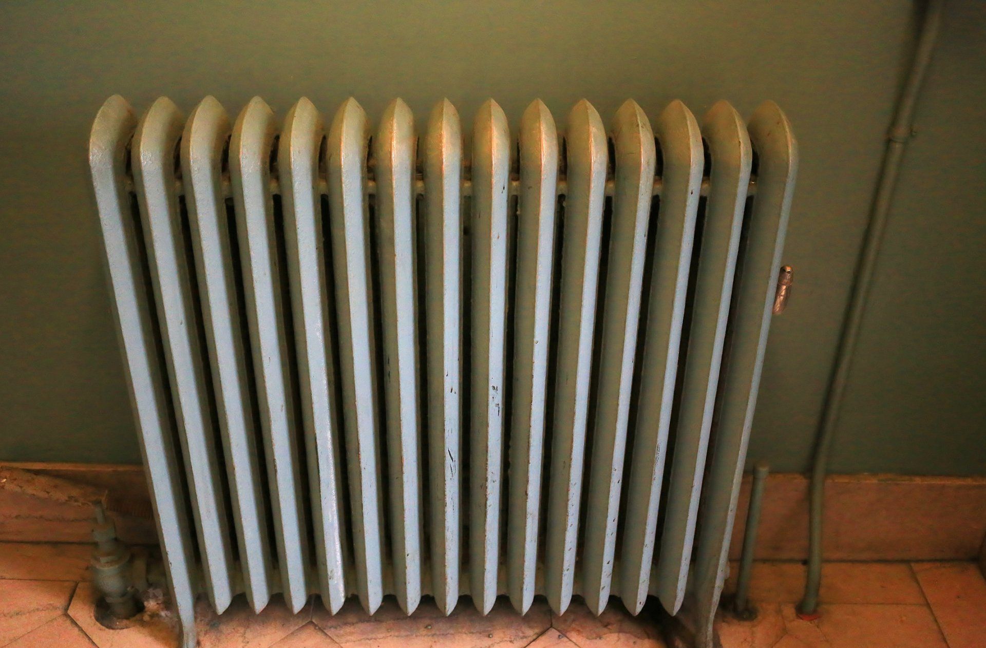 Electric Heater — Springville, UT — Blue Plumbing and Drain Cleaning A radiator is sitting on a tiled floor next to a wall.