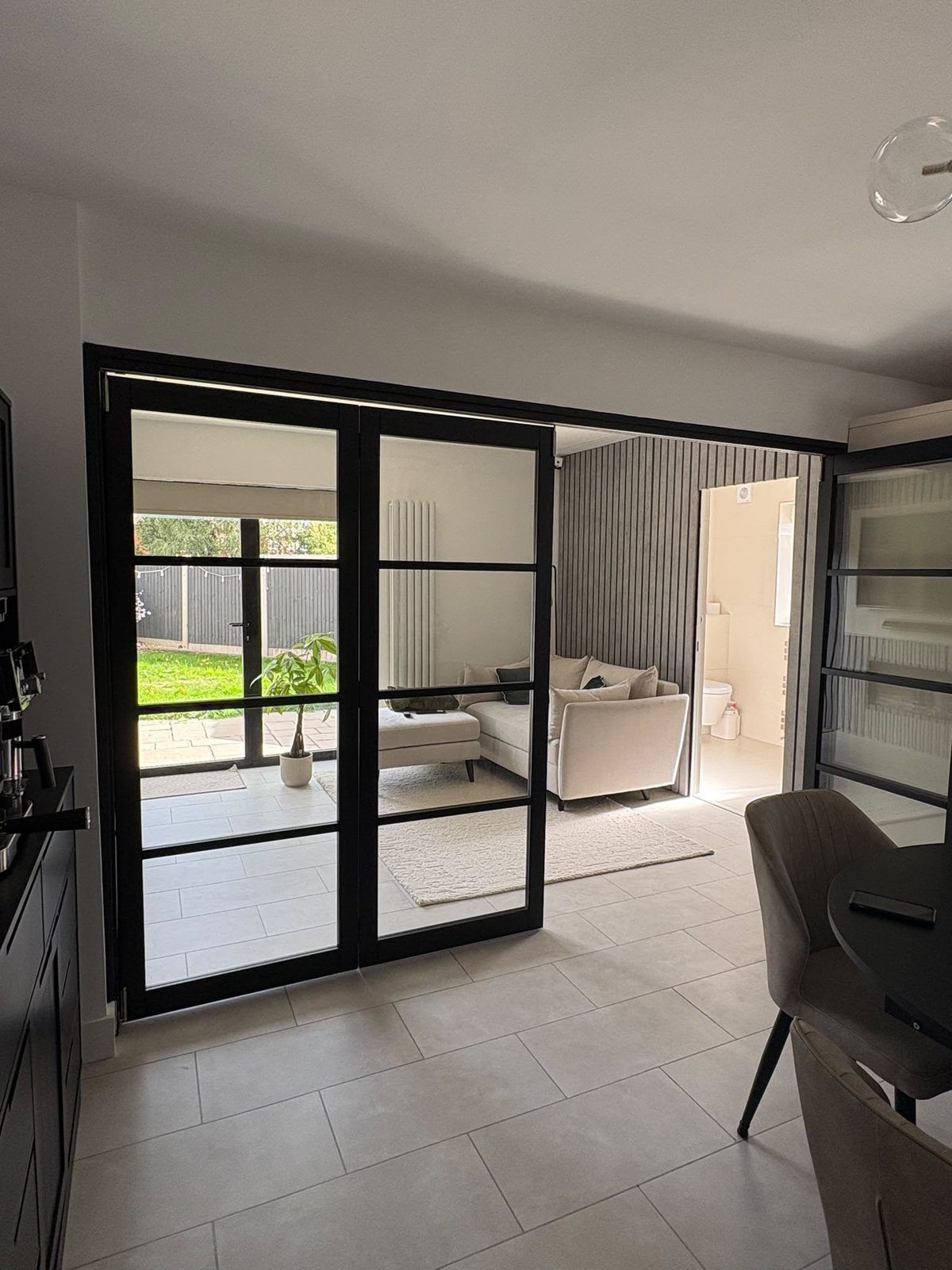 Black-framed glazed internal bifold doors closed between a kitchen-diner and a rear extension lounge