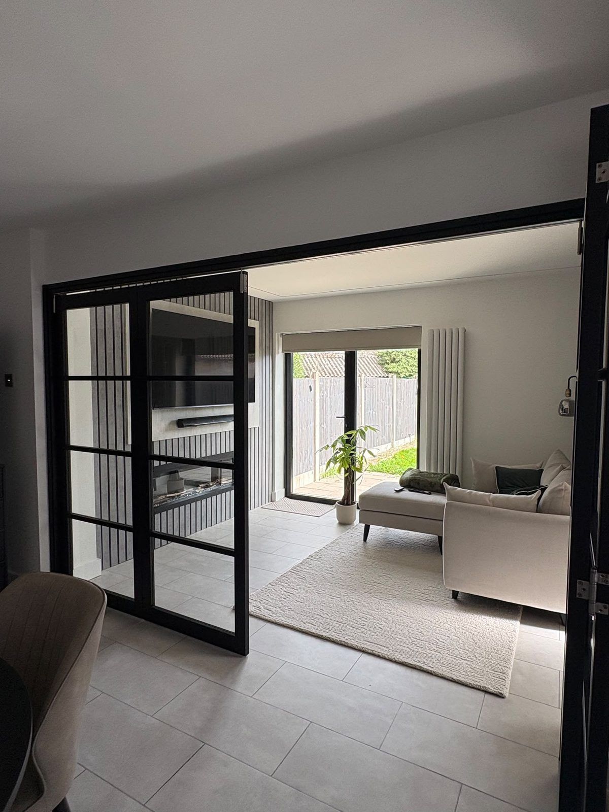 Glazed internal bifold doors folding open onto an extension lounge with a slatted media wall