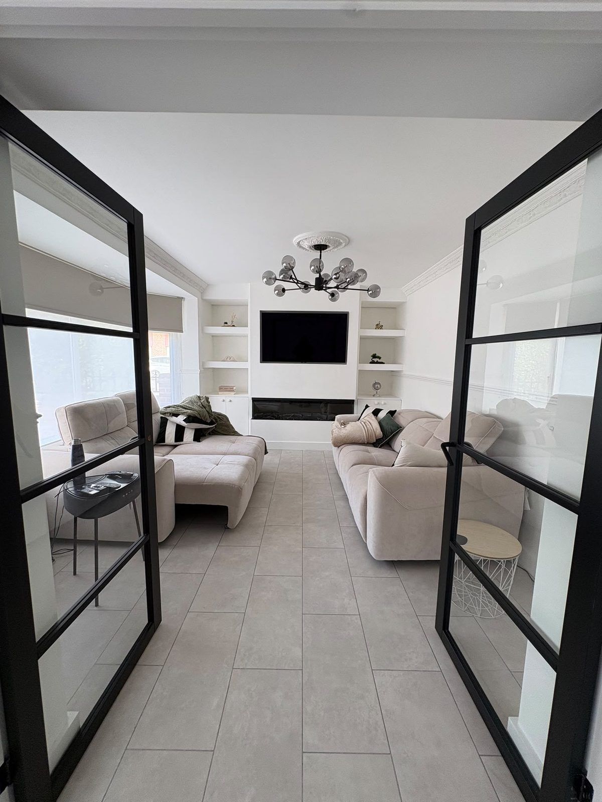 Lounge media wall with built-in alcove shelving, cupboards and a long electric fire