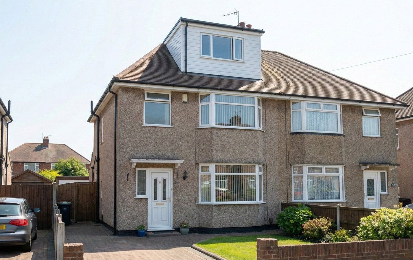 Front exterior view of a semi-detached house, with a finished white dormer conversion visible on the hip roof.