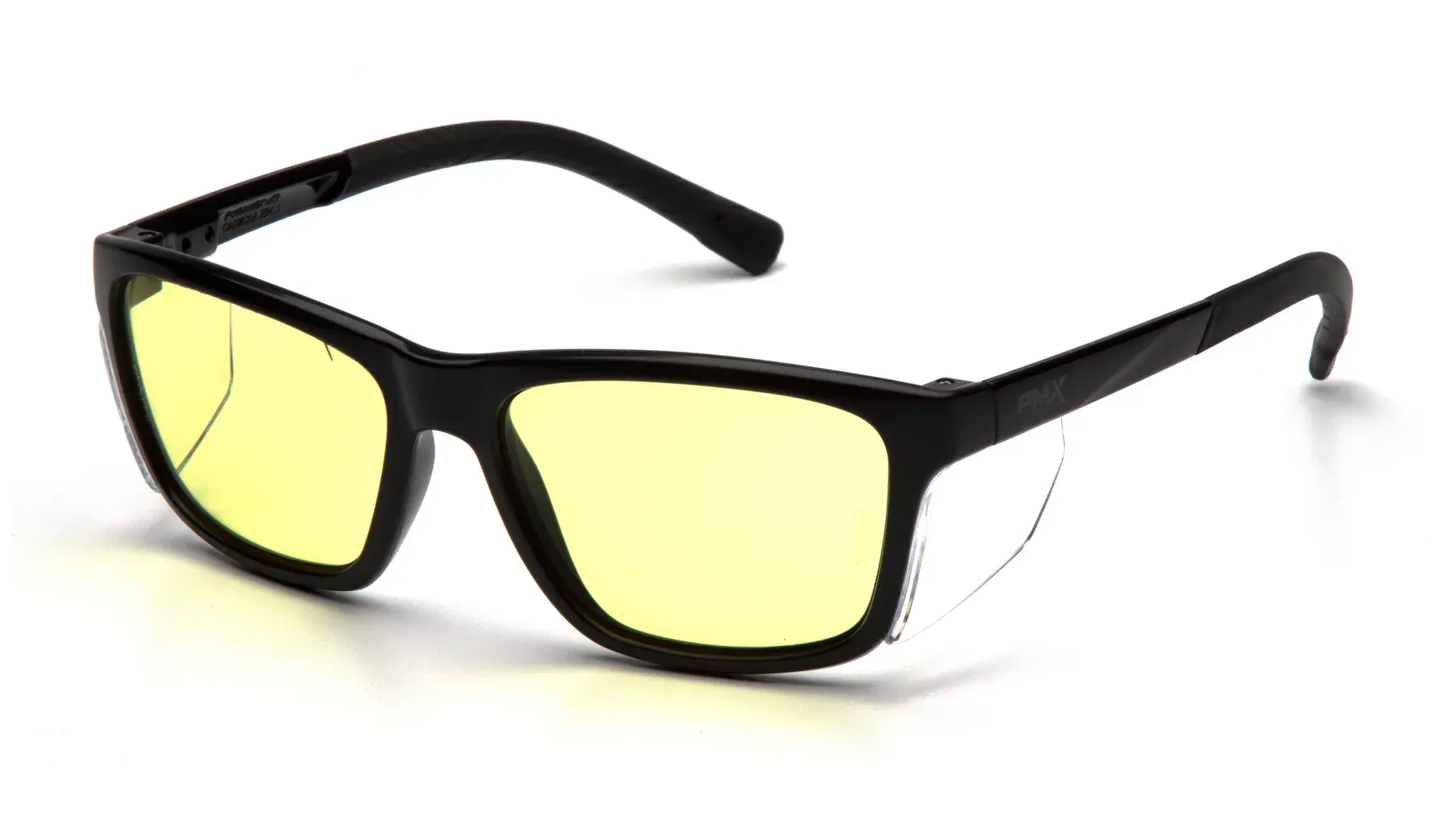 Gafas con montura negra, lentes amarillas y protectores laterales, apoyadas sobre una superficie blanca.