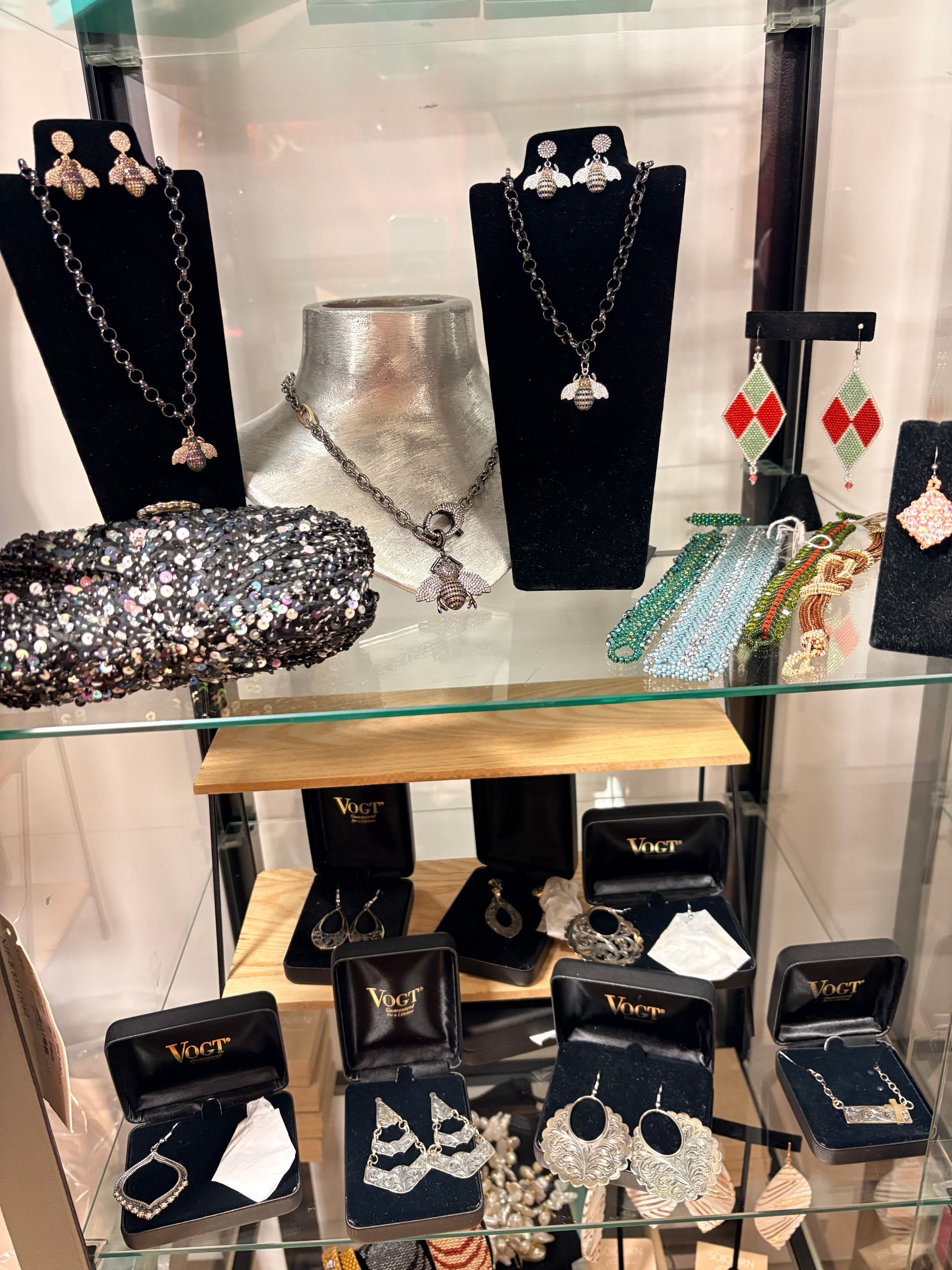 Jewelry display case with necklaces, earrings, bracelets, and rings on black stands and boxes