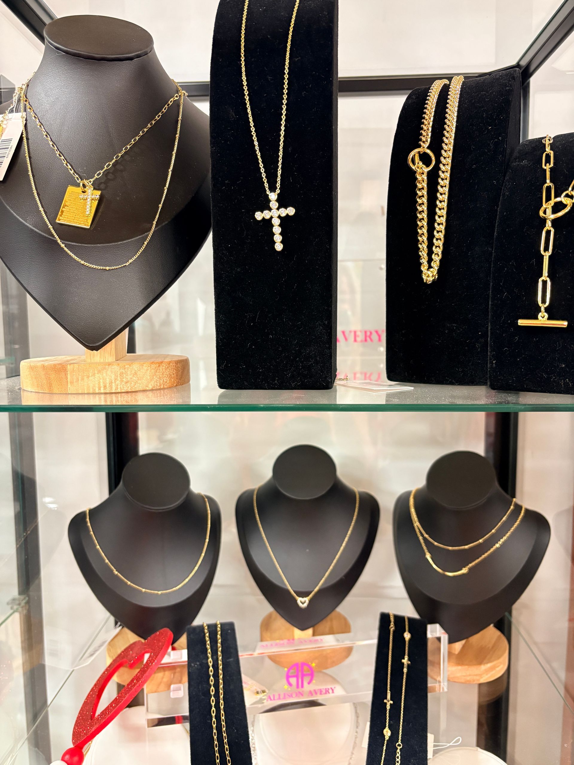 Jewelry display of gold necklaces on black bust stands and trays in a shop window
