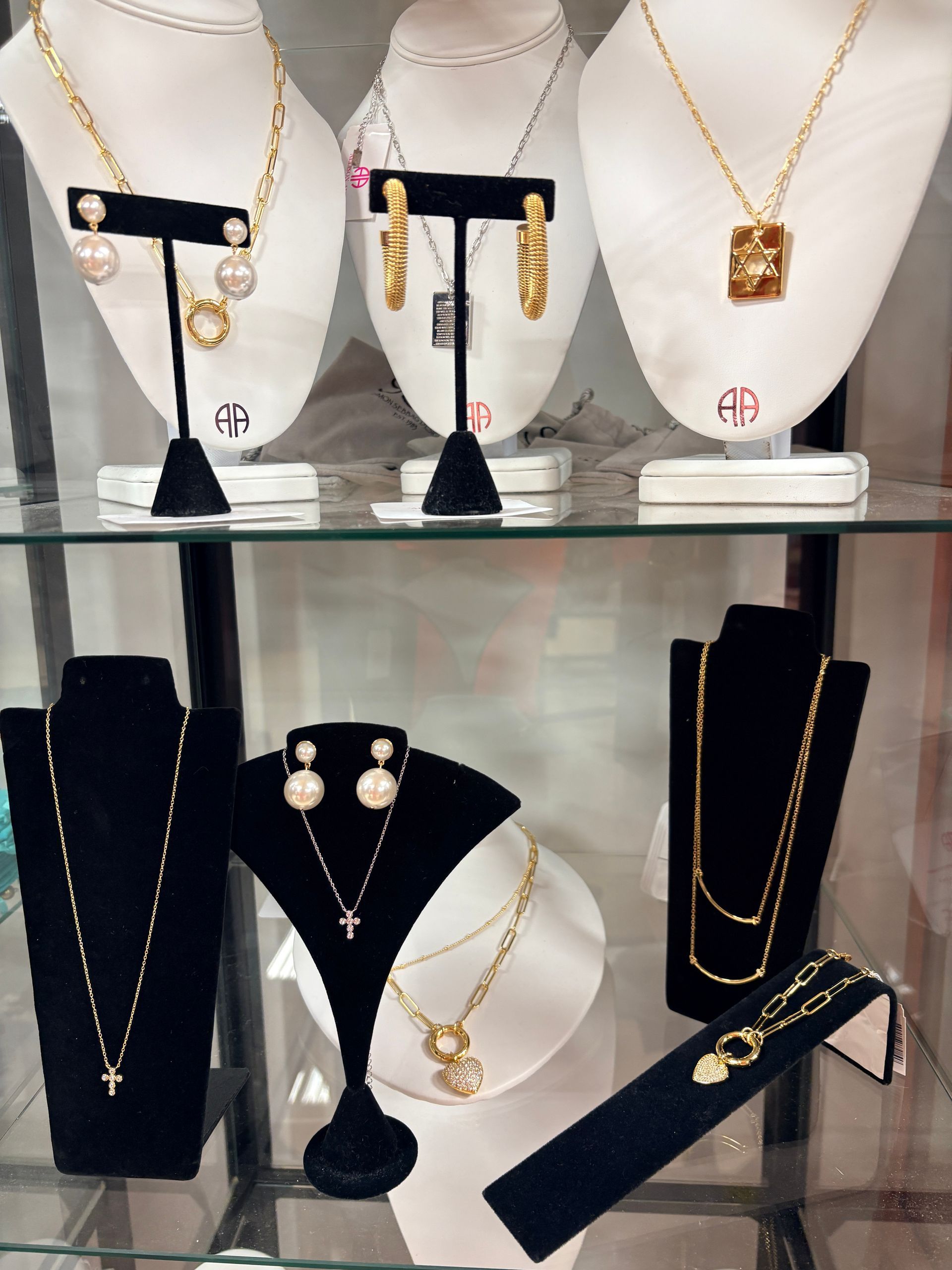 Gold jewelry sets displayed on black velvet busts in a store showcase.