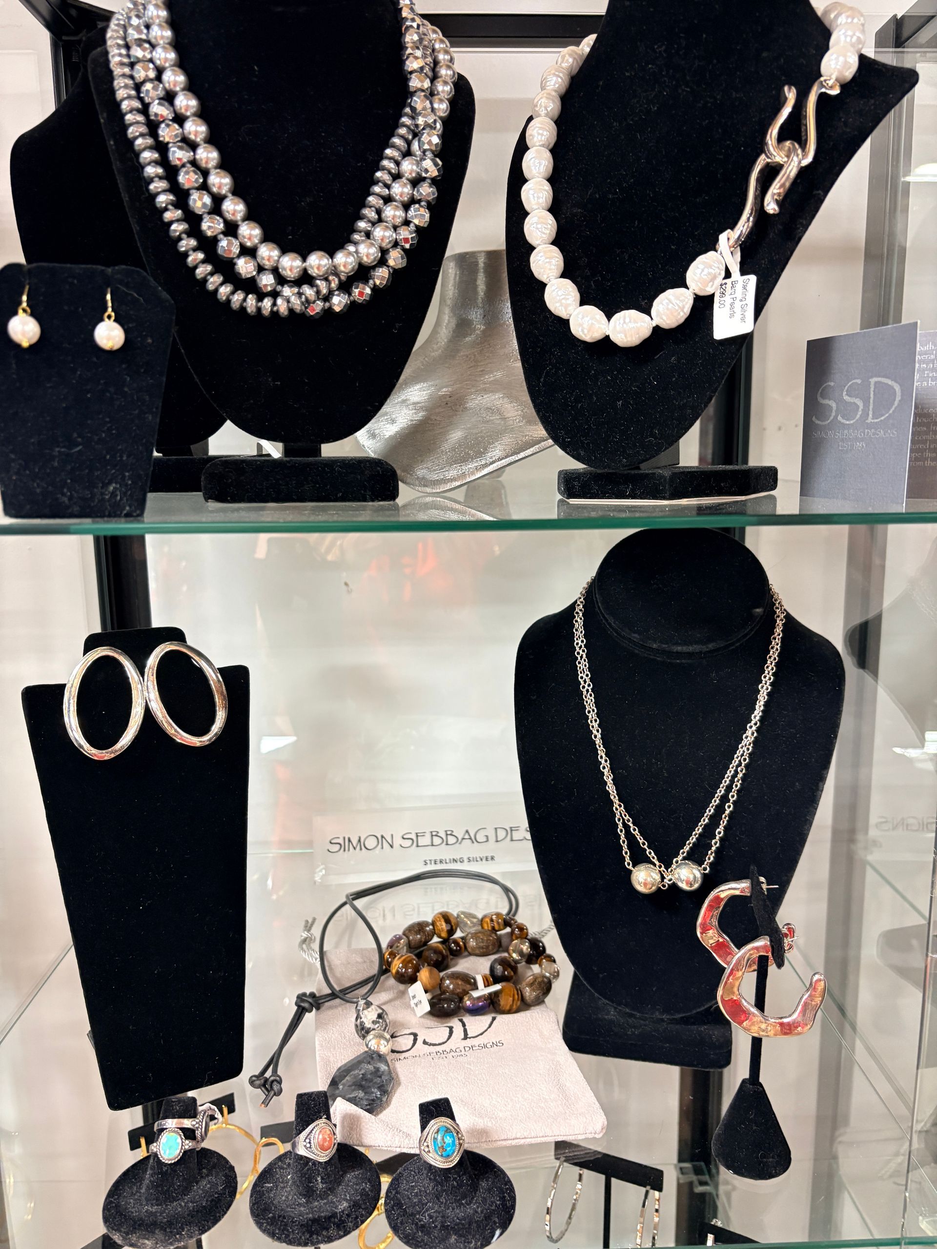 Jewelry display with pearl necklaces, earrings, bracelets, and ring stands in a glass case