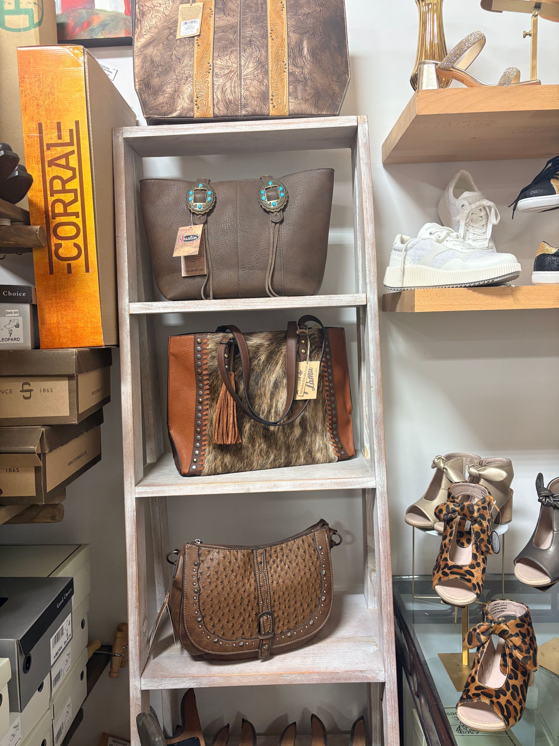 Shelves of handbags and accessories displayed in a boutique, with neutral and brown tones.