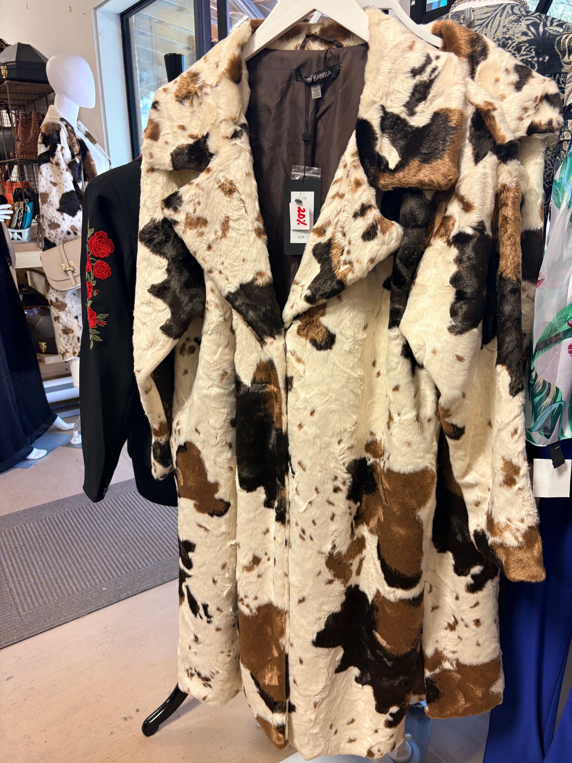 Cowhide-patterned coat hanging on a clothing rack in a store