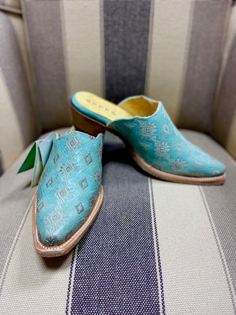 Turquoise embroidered slip-on shoes on a striped chair seat.