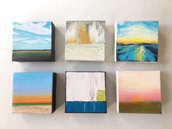 Framed impressionist painting of a seaside path with trees, blue water, and a white building in a wooden tray.
