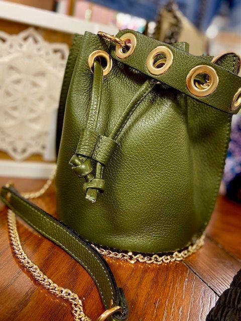 Green drawstring pouch with gold grommets and trim on a wooden surface