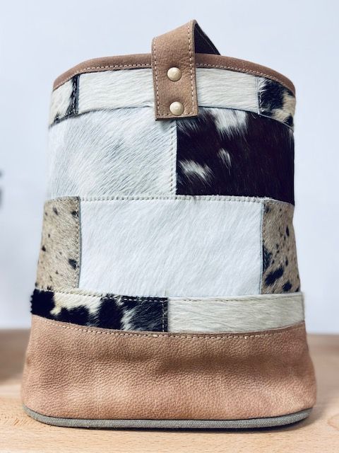 Patchwork fur bucket bag in white, black, and tan with leather trim and handle strap