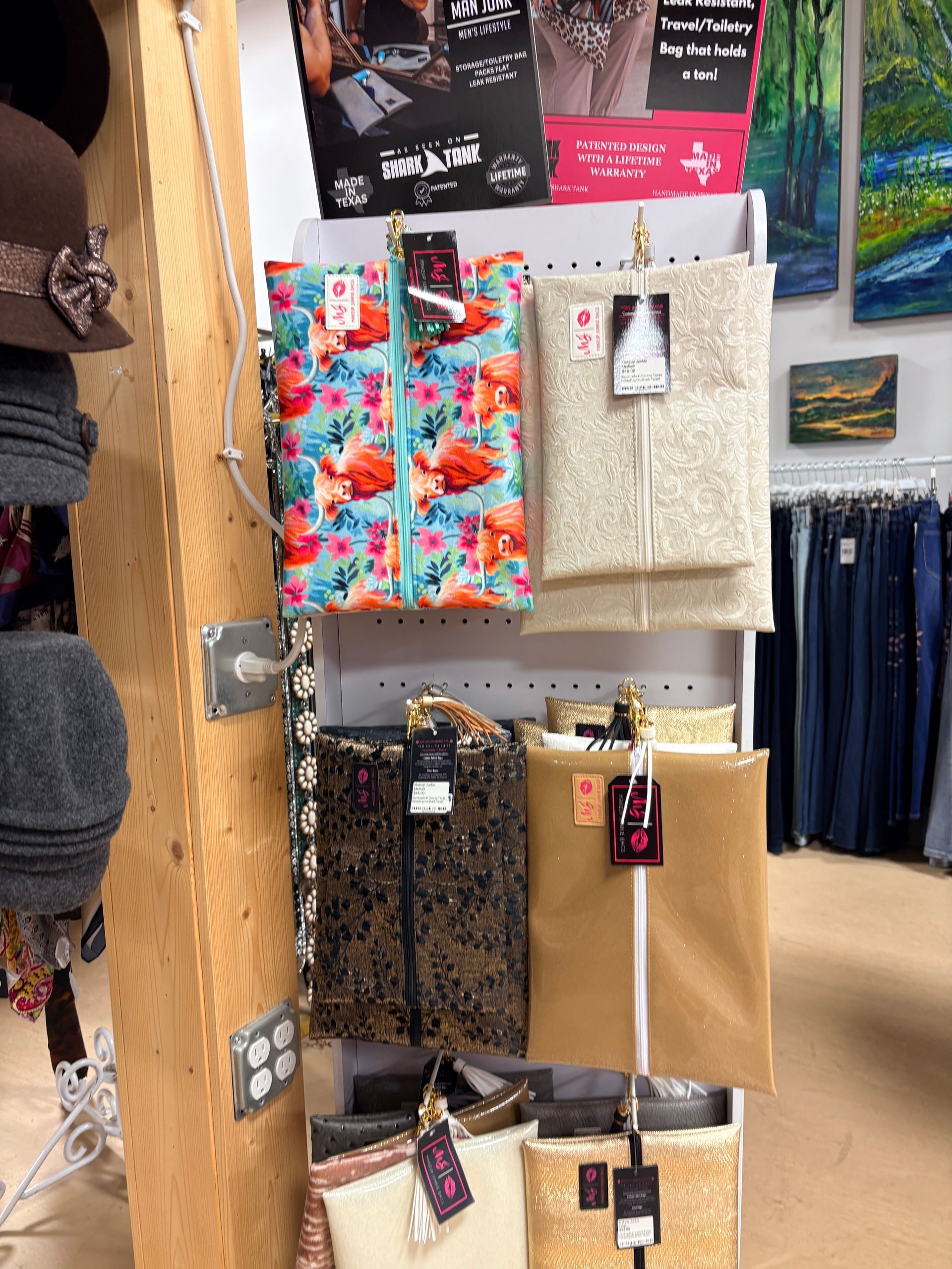 Retail display of colorful patterned tote bags and wallets hanging on a shop wall