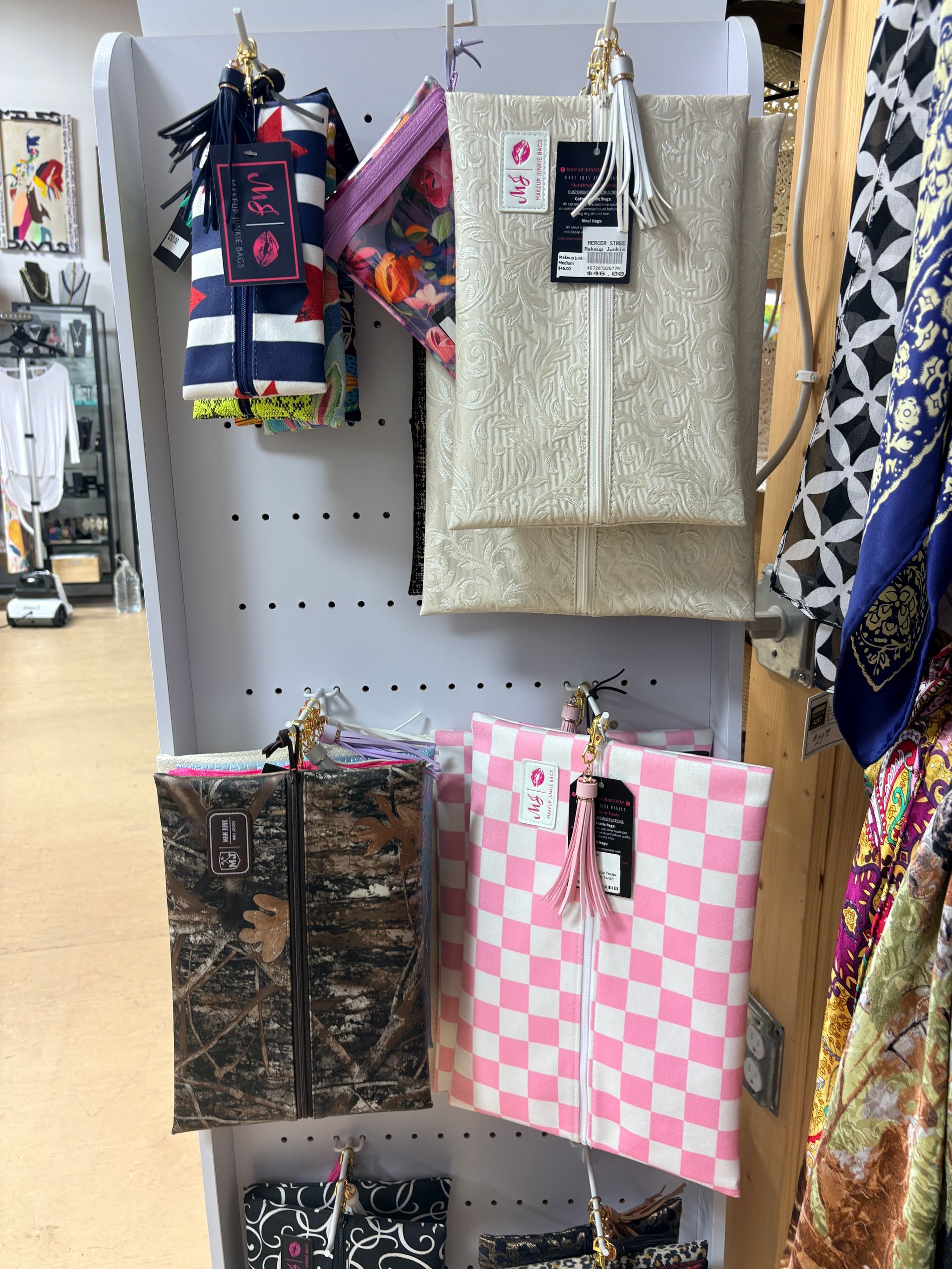 Store display of hanging and folded patterned bags in beige, pink, and black on a retail shelf