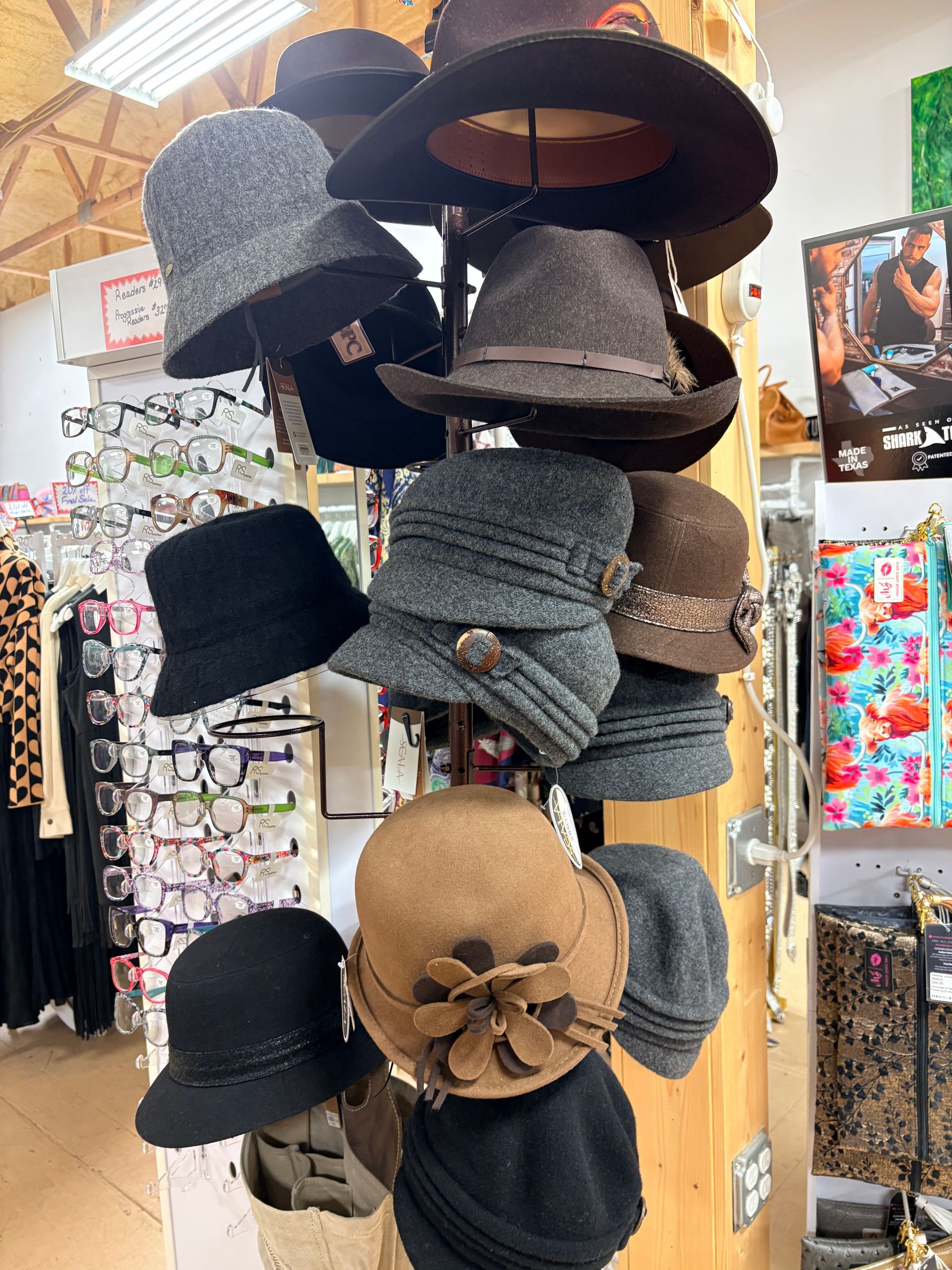 Display of assorted hats hanging in a shop, including black, gray, and beige styles.