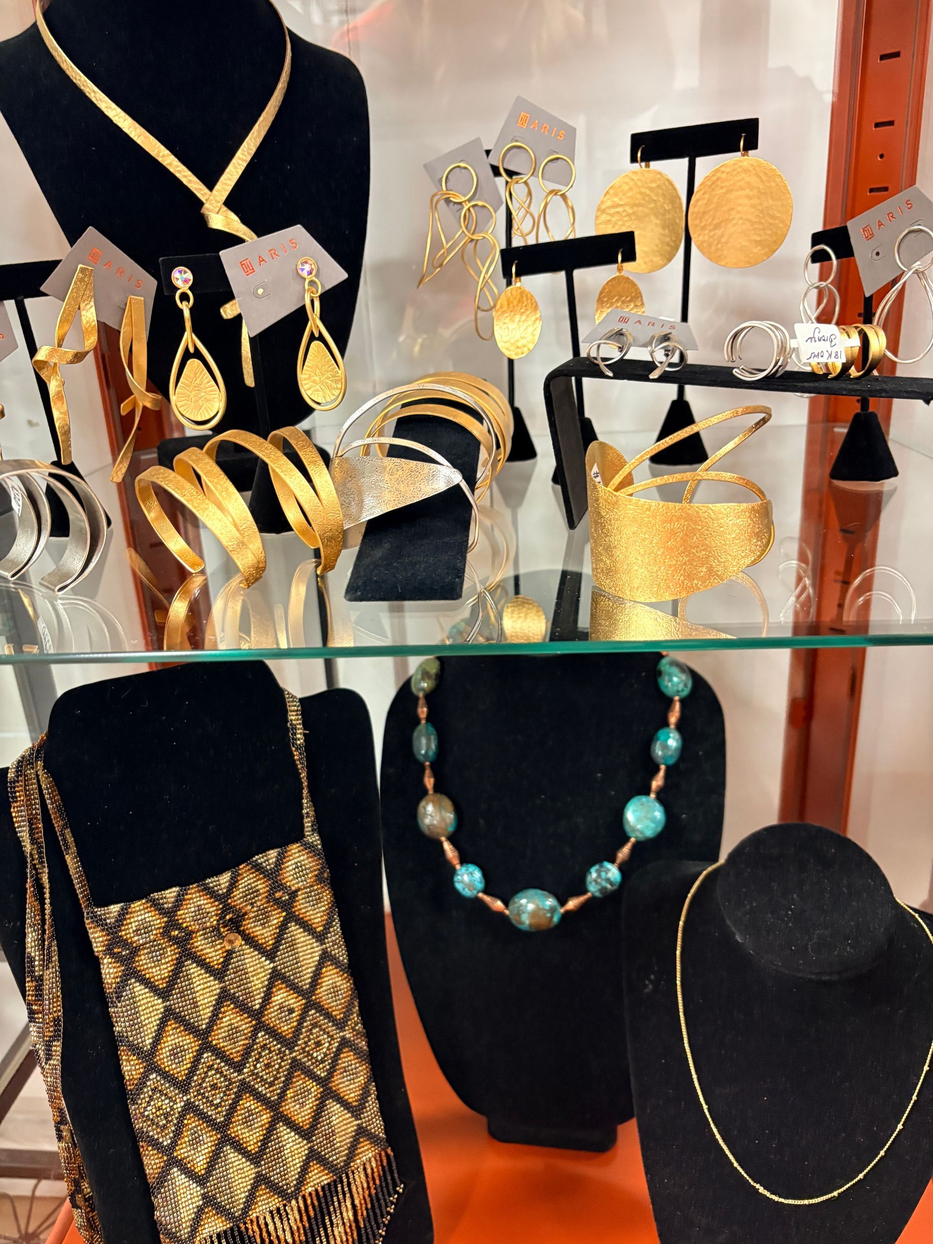 Jewelry display with gold and turquoise necklaces, earrings, bracelets, and decorative stands