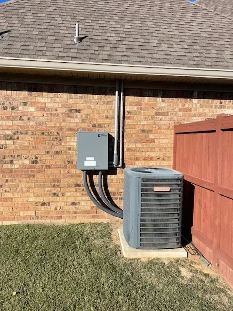 AC unit against brick wall with electrical box and conduit.
