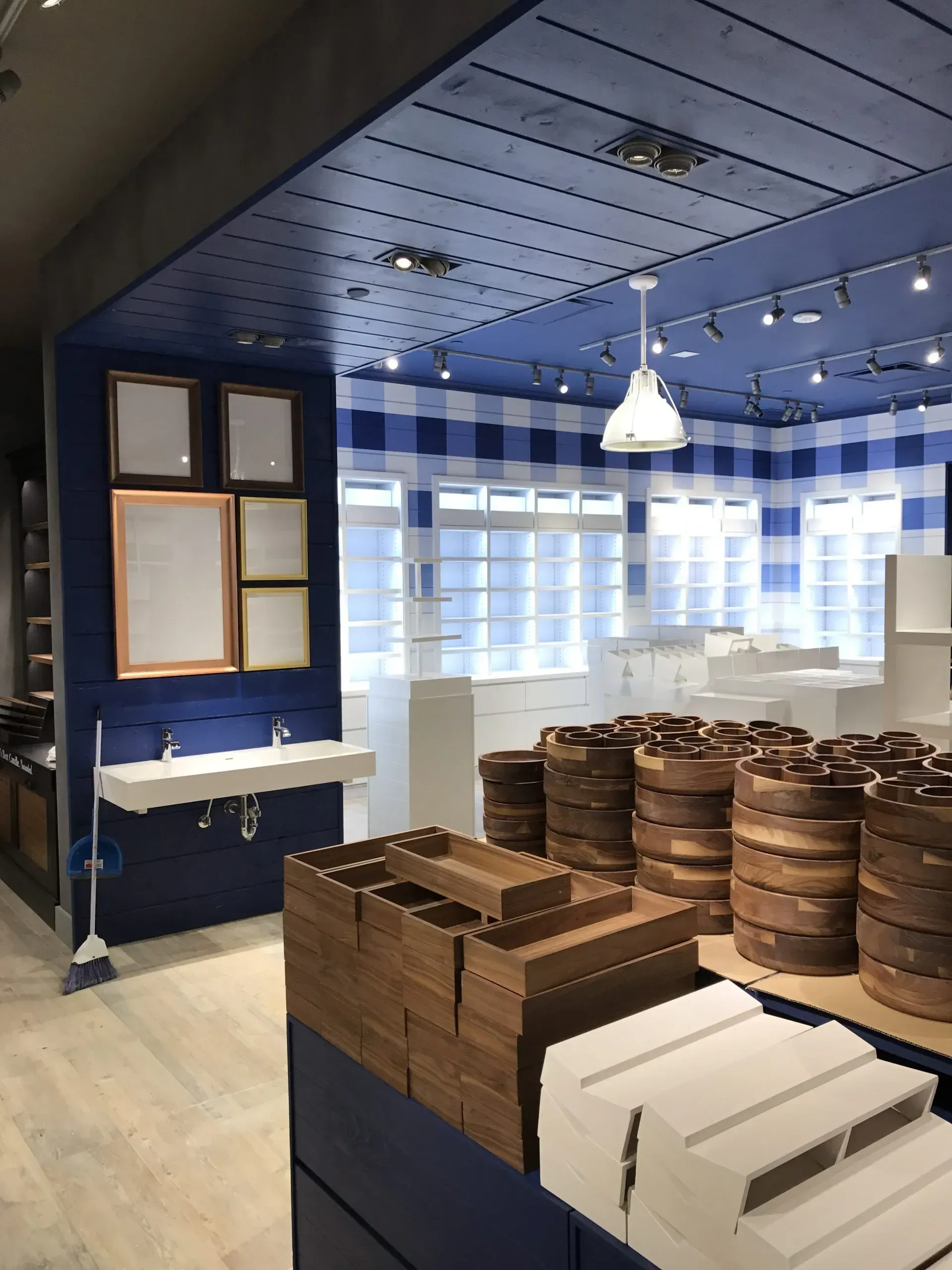 Blue and white store interior with wooden displays, framed pictures, and barrels.