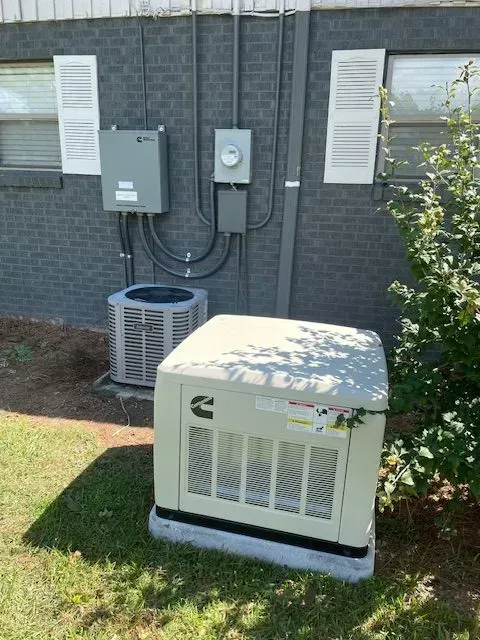 An exterior shot shows a generator, air conditioner, and electrical boxes mounted on a brick wall.