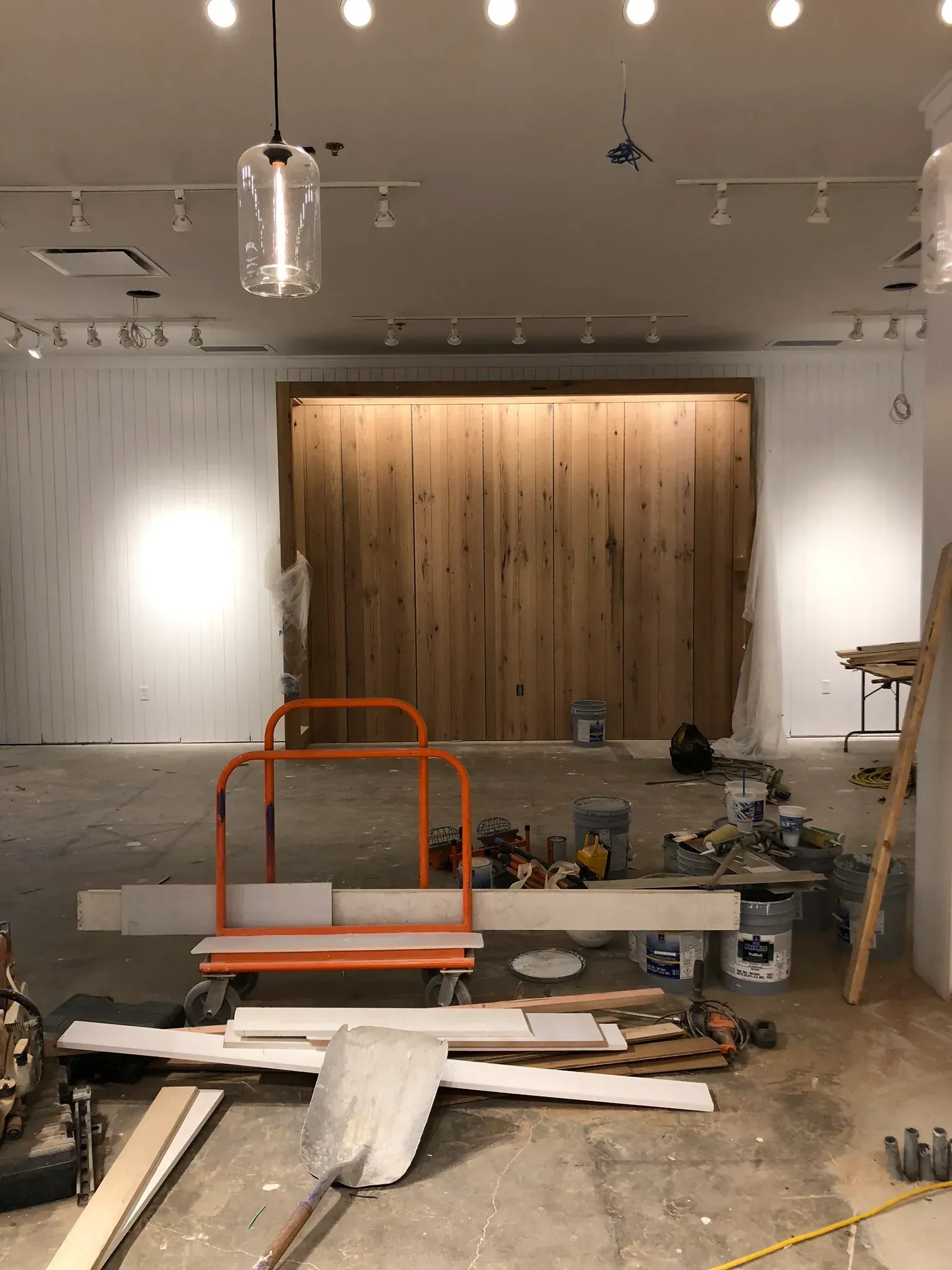 Interior construction site with tools, supplies, and wooden wall display.